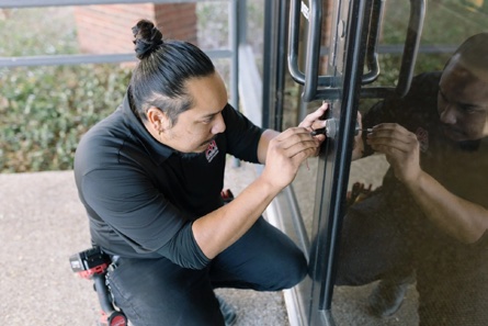 An A-1 Locksmith technician working on a commercial glass door lock