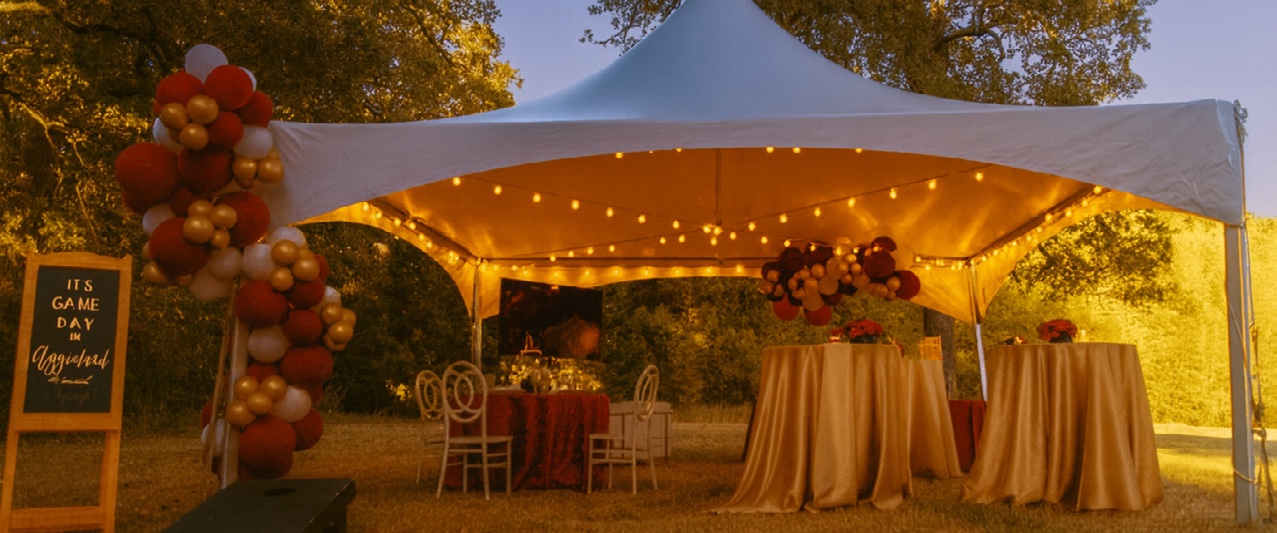 A TopTec tent lit with string lights over a decorated evening event